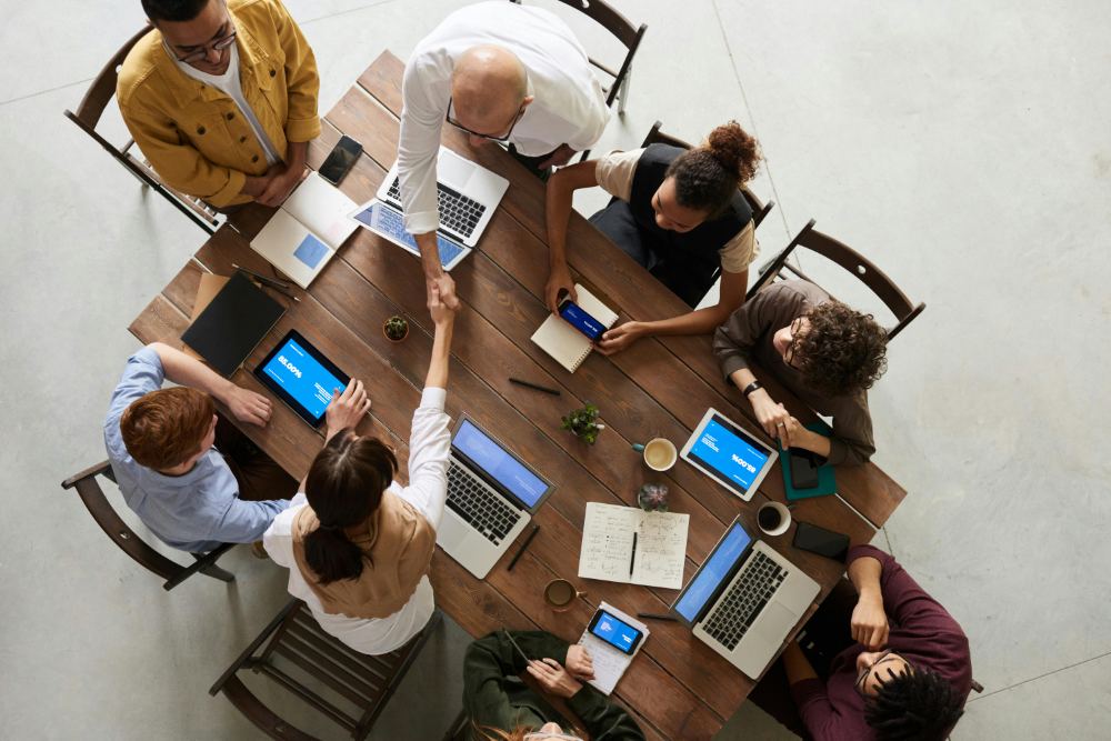 A team gathered around a shared work table at a kickoff meeting, seen from above