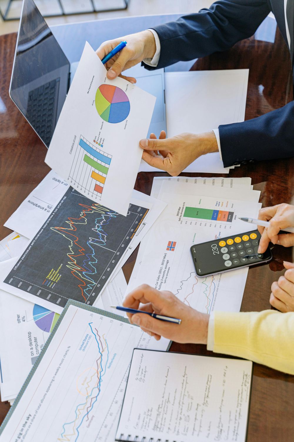 Hands reviewing printed analytics charts spread across a desk