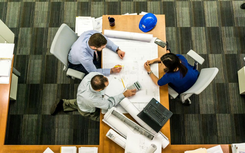 Engineers reviewing construction blueprints together around a work table